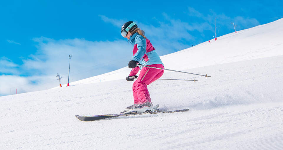 Kvindelig skiløber står på ski ned af hvid pist